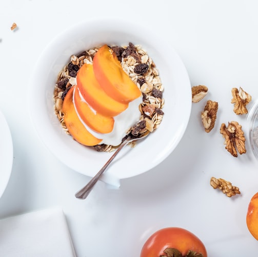 bowl of cereal with sliced fruits and spoon