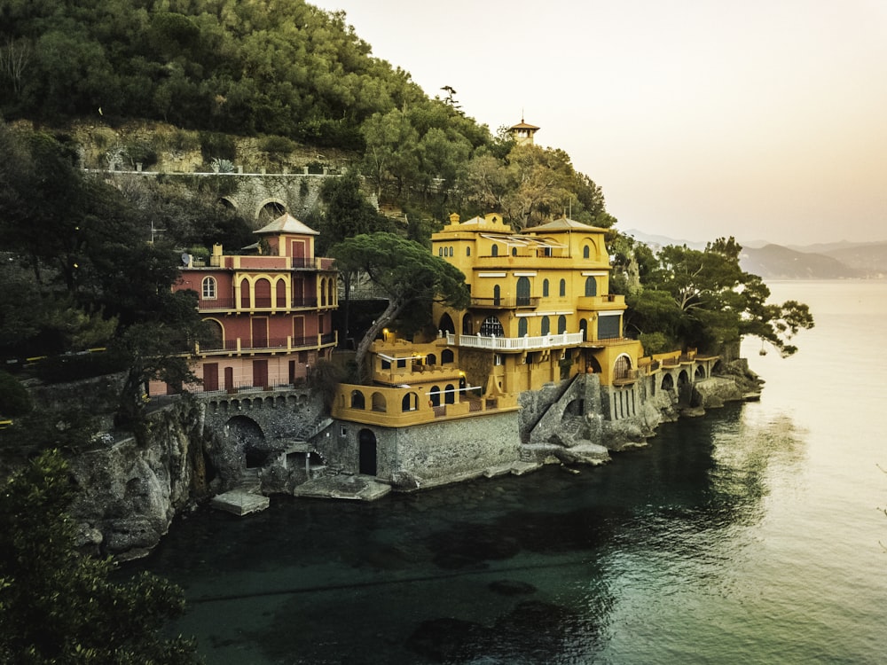 yellow concrete building beside body of water surrounded with green trees at daytime