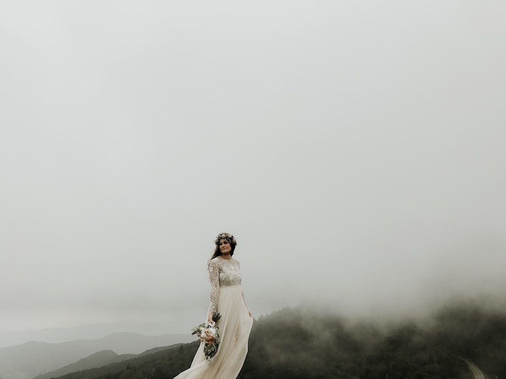 mulher vestindo vestido de casamento em pé no topo da colina