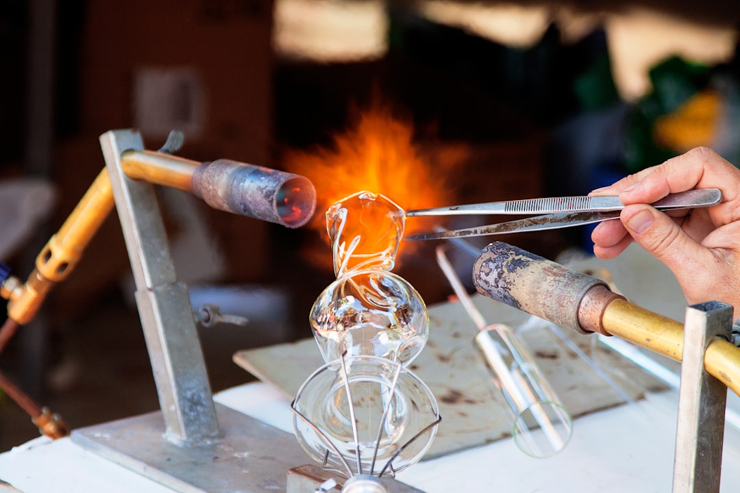 person molding glass vase through blowtorch