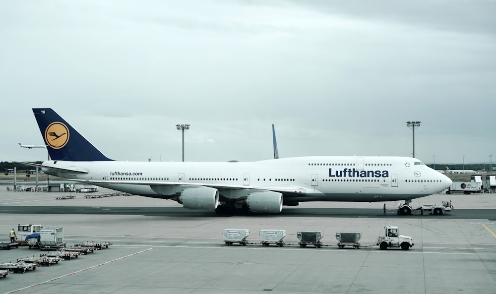 avião comercial branco e preto da Lufthansa perto de veículos