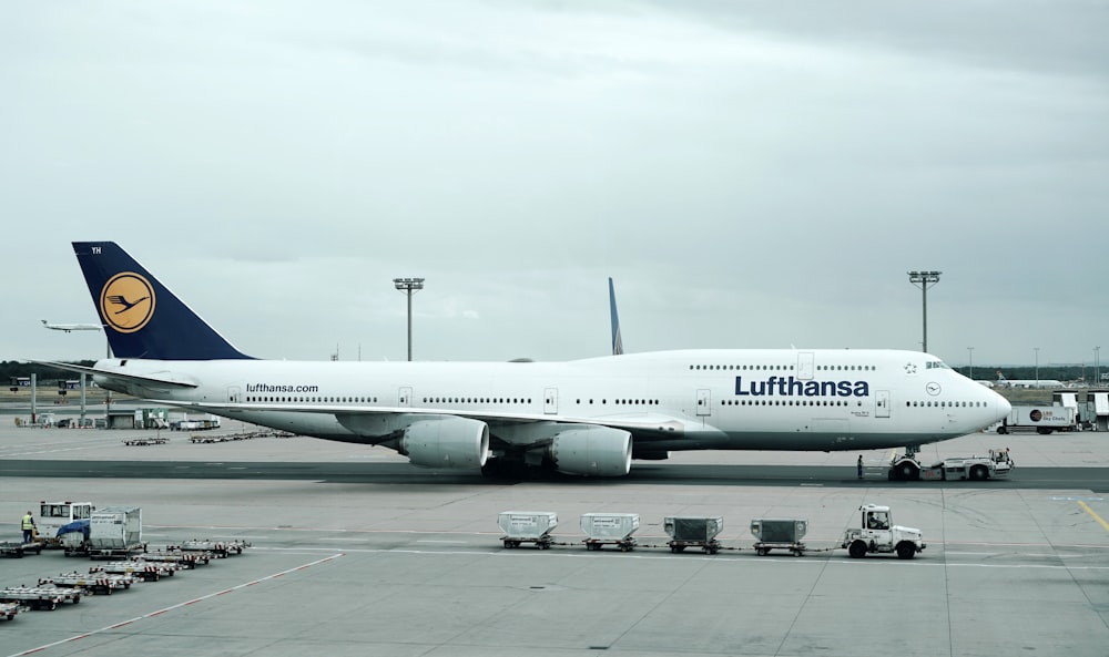 white and black Lufthansa airliner near vehicles