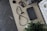 A tabletop with various items including a handheld gaming device, a pair of wired earphones, a plant, a camera lens cap, and a collection of game cartridges in a holder. There are also some stickers featuring colorful designs and characters.