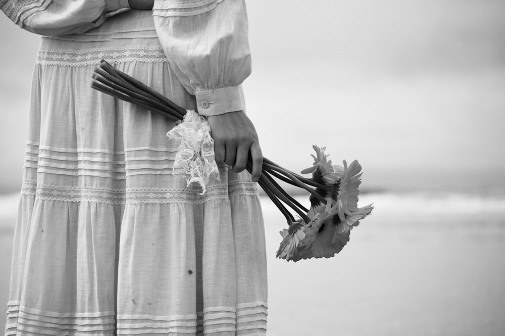 Persona que sostiene un ramo de flores en la playa