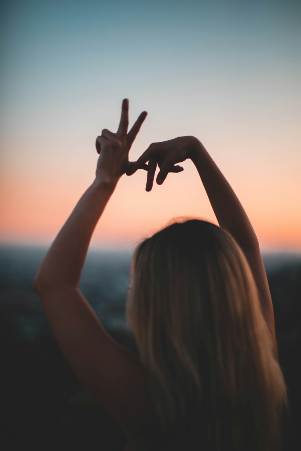 woman doing hand sign during golden hours