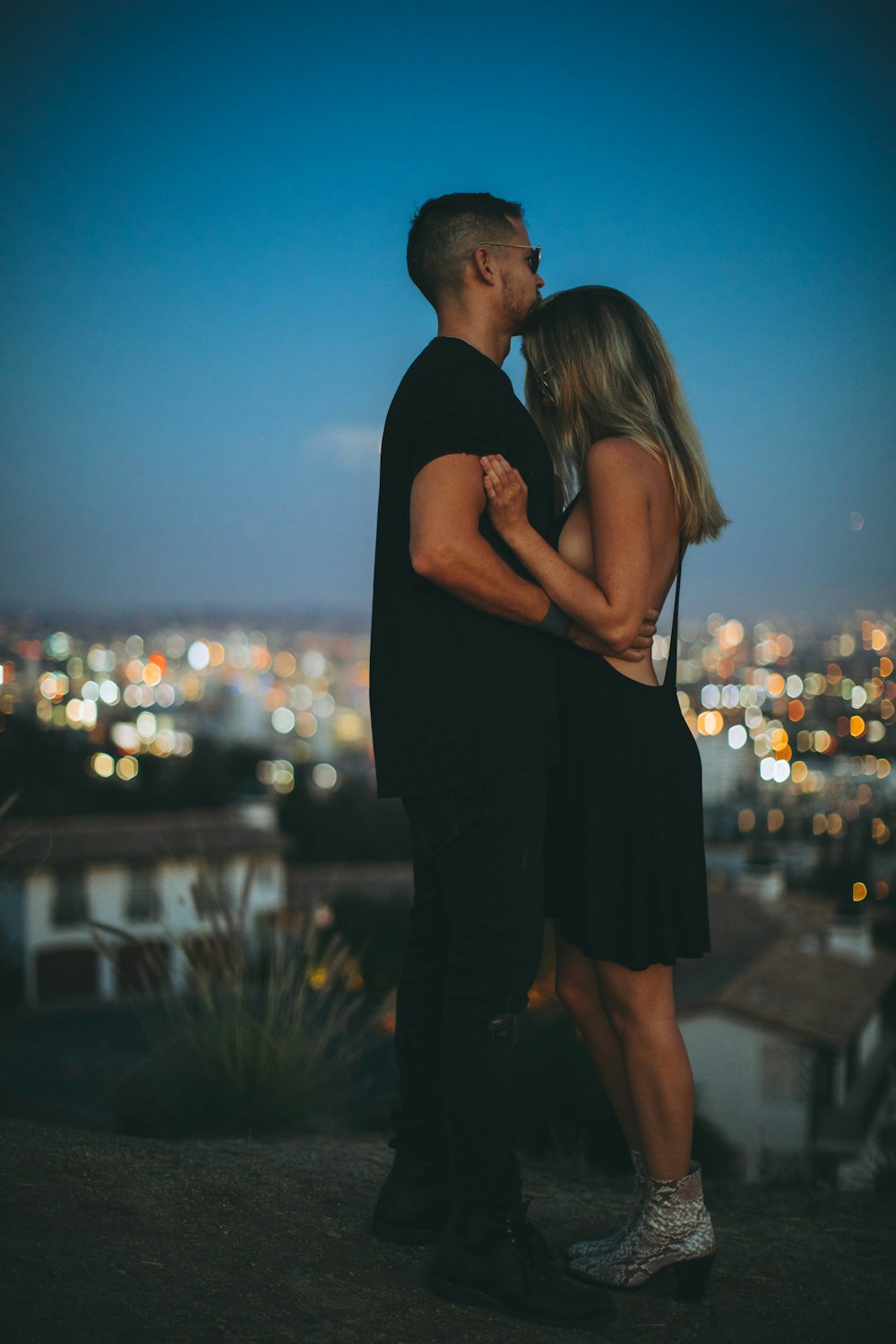 uomo che abbraccia la donna in cima alla collina durante la notte