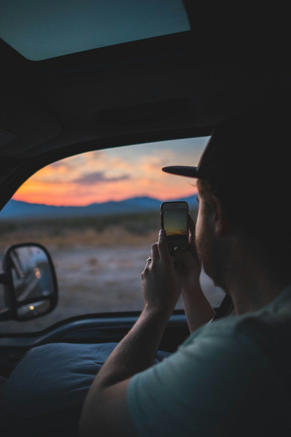 man holding smartphone with sitting on bucket seat inside car