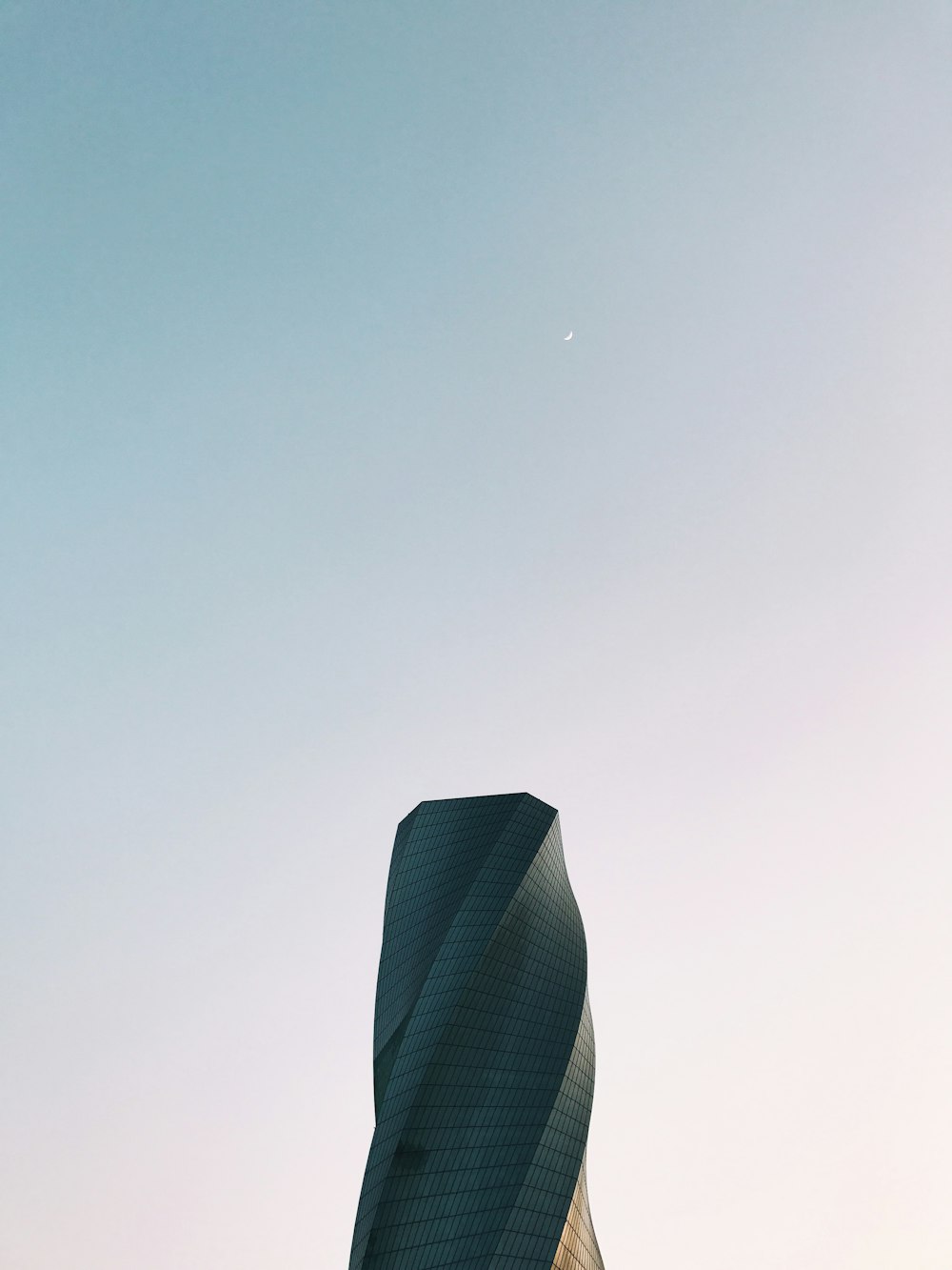 Fotografie aus der Wurmperspektive des grauen Turms unter klarem Himmel