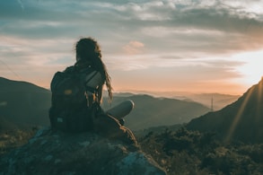 woman sitting on rock carrying black backpack