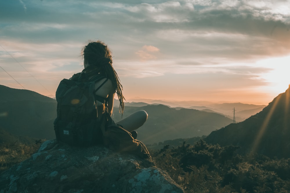woman sitting on rock carrying black backpack