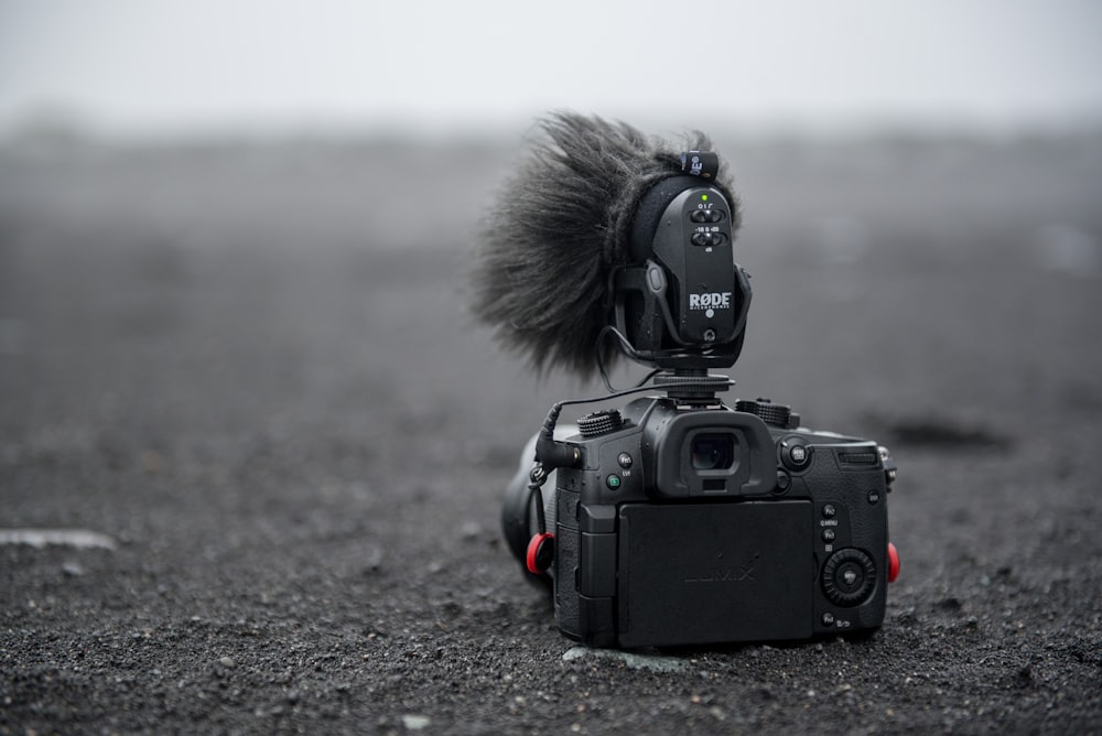 photo en niveaux de gris d’un appareil photo reflex numérique sur le sable