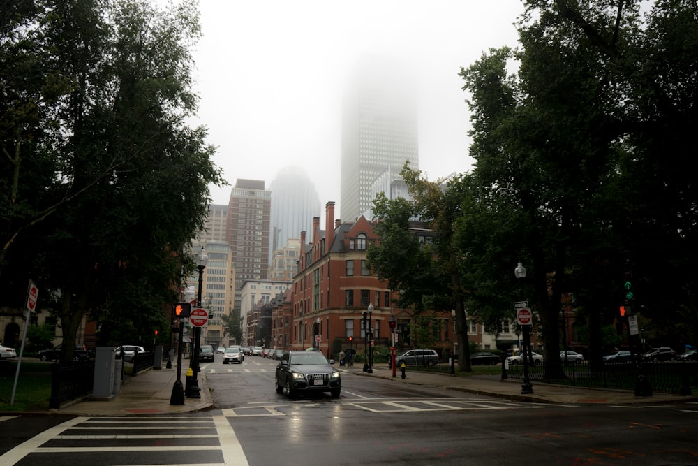 a foggy city street with cars driving on it