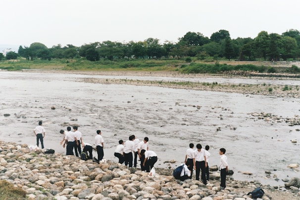 Faculty members and students participating in an outdoor environmental field study near a riverbank.