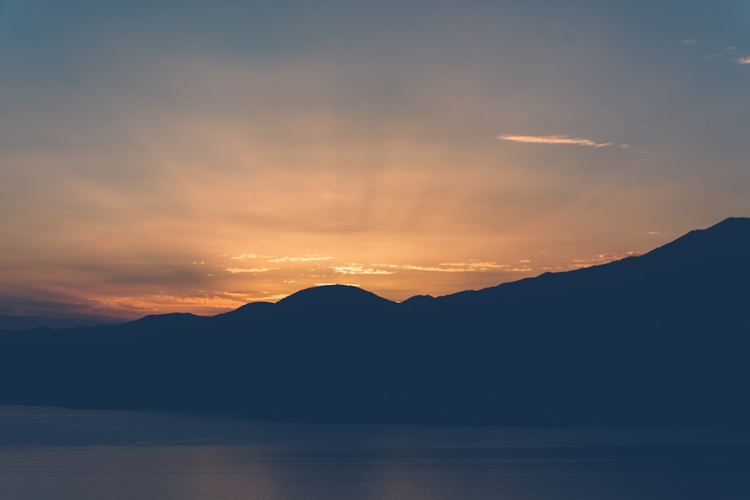 silhouette of mountains near body of water during golden hour