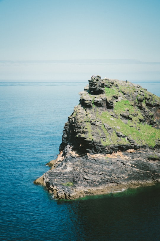 person standing on boulder on body of water in Boscastle United Kingdom