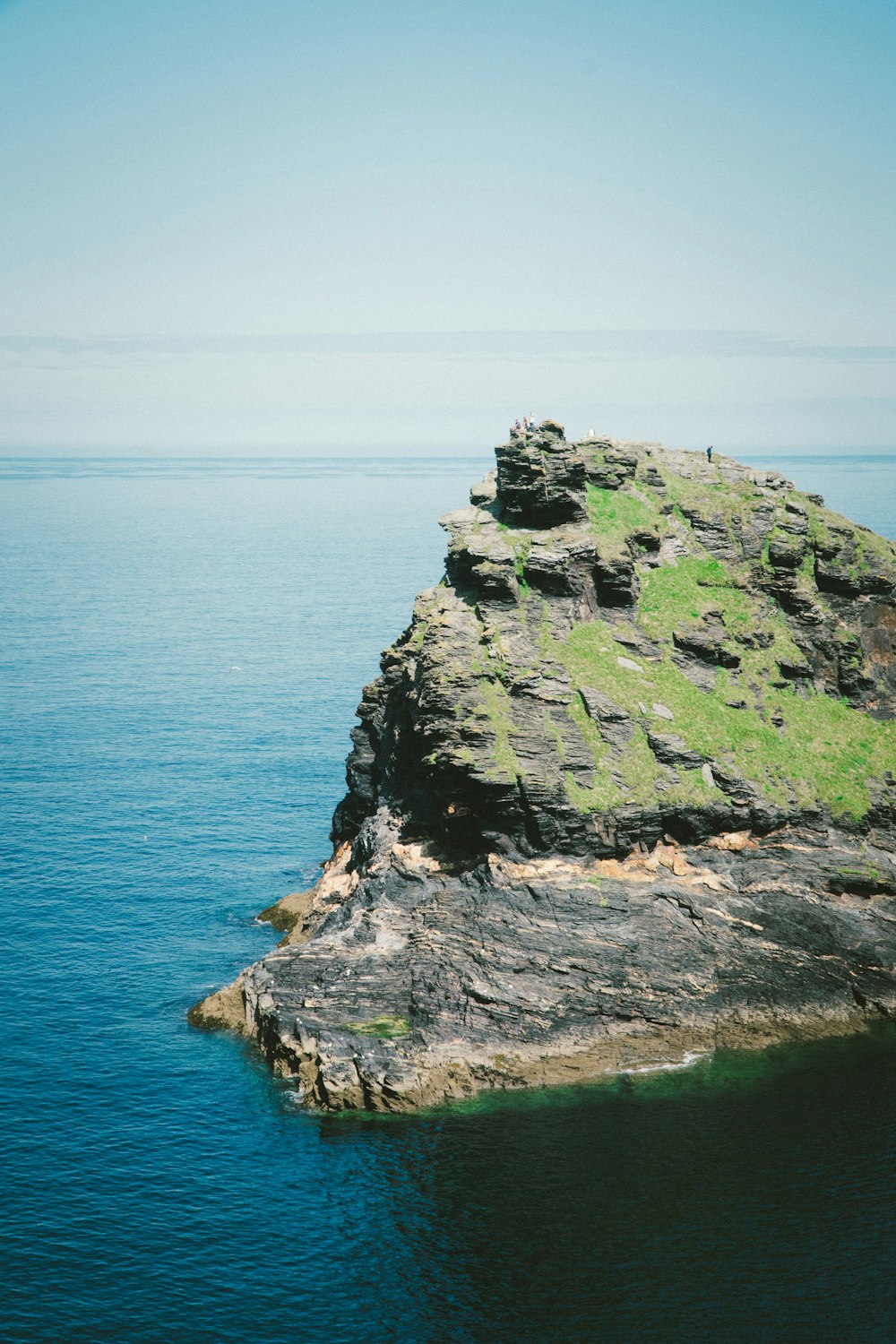 person standing on boulder on body of water