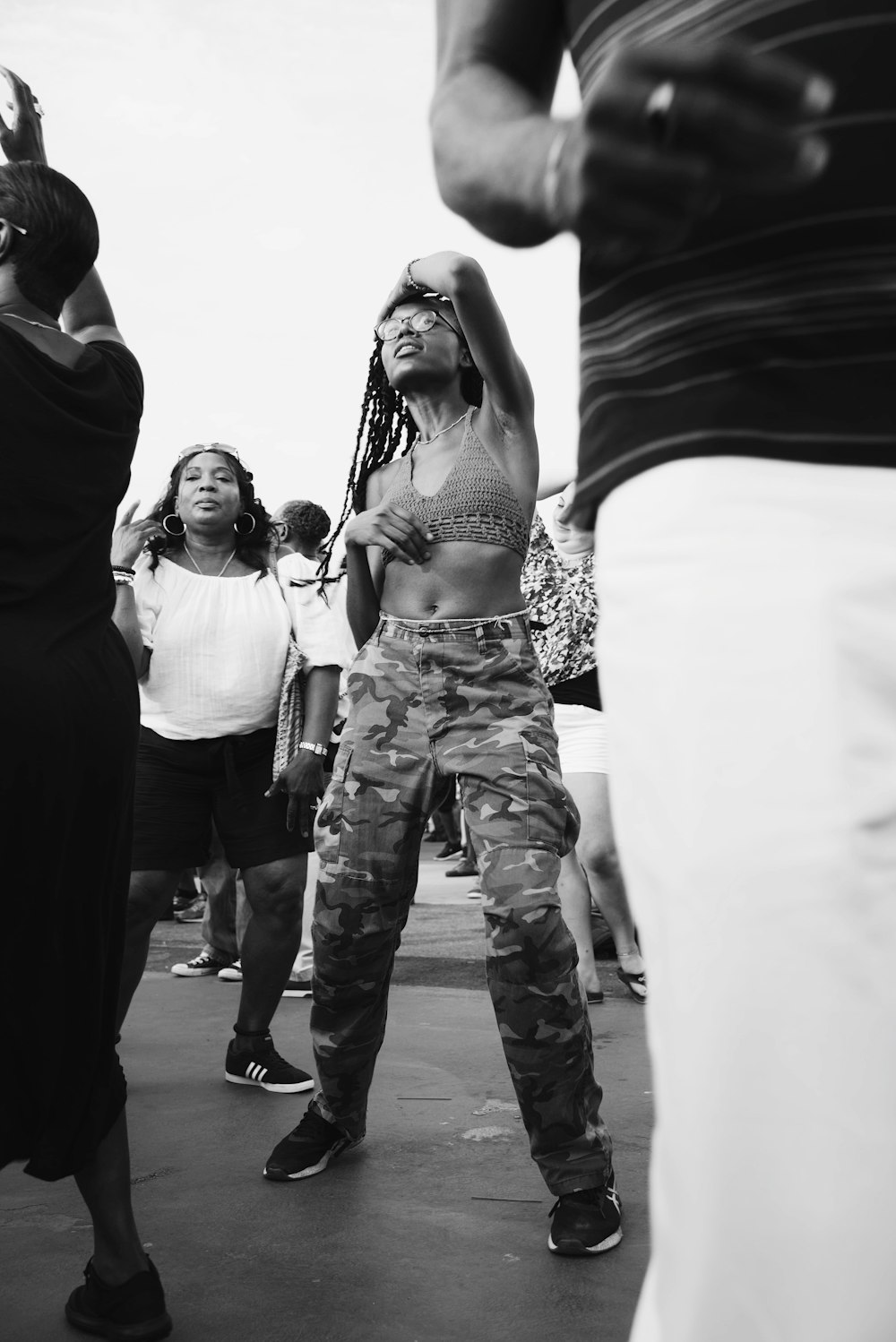 grayscale photo of woman dancing surrounded by people