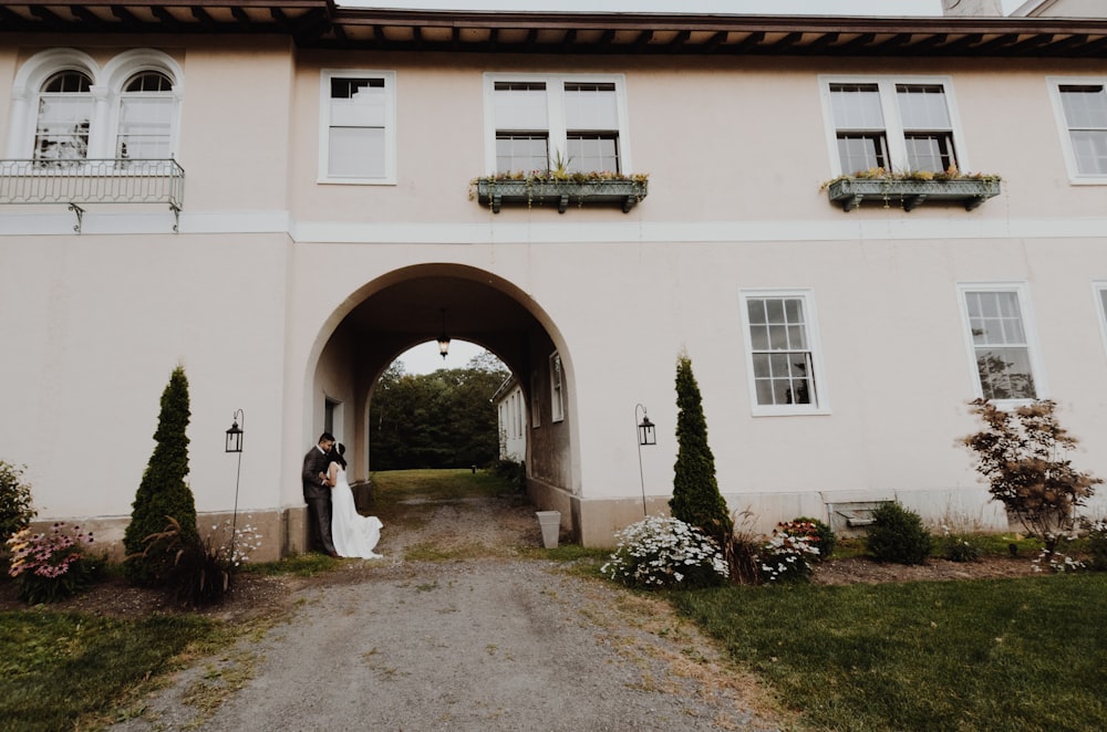 groom and bride leaning on white concrete building