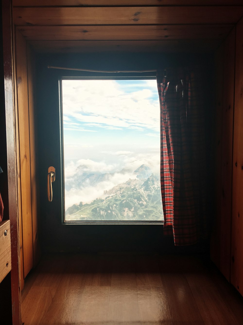 closed black wooden framed window with red plaid curtain