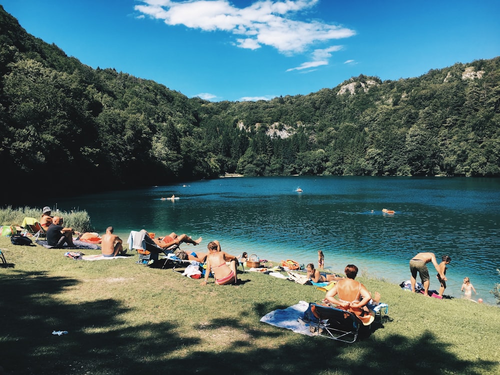 group of people gathering near lake under blue sky during daytime