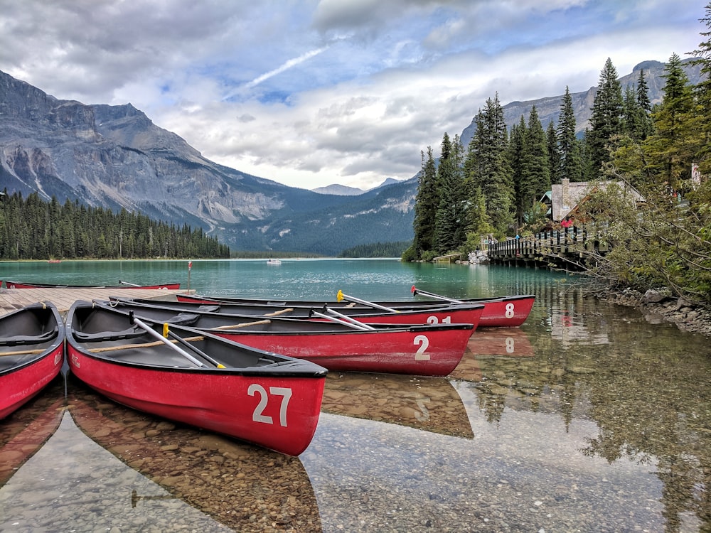 four red canoes on body of water