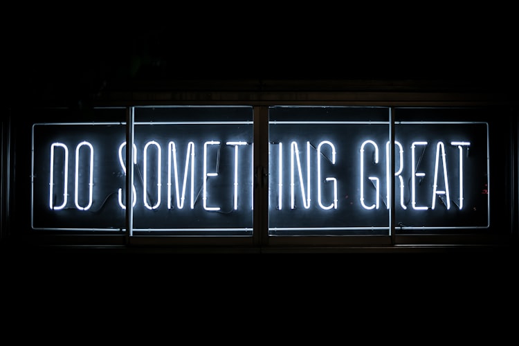 A white neon sign that says Do Something Great