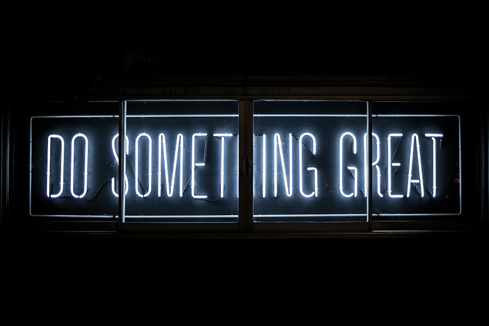 A white neon sign that says Do Something Great