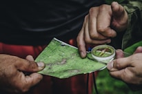 Close-up of hands holding a detailed map with travel notes and a compass.