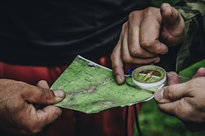 Close-up of hands holding a map and compass on a wooden boat table