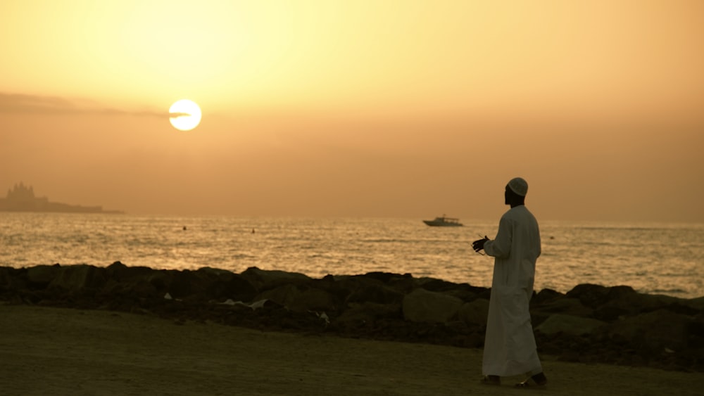 man walking on road beside shore