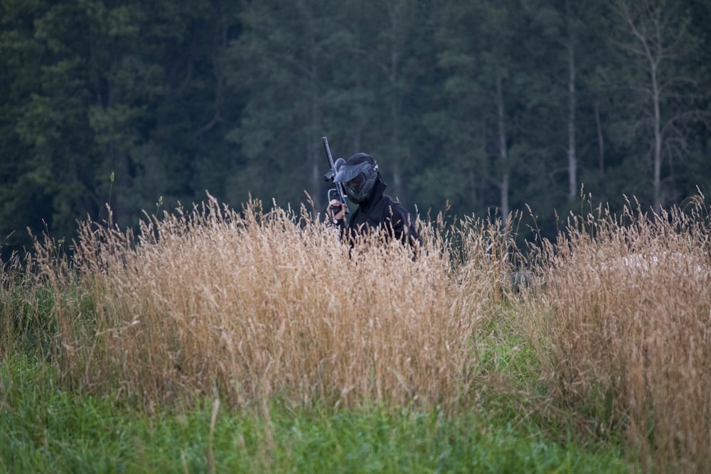 person standing beside brown and green grass near green high trees during daytime