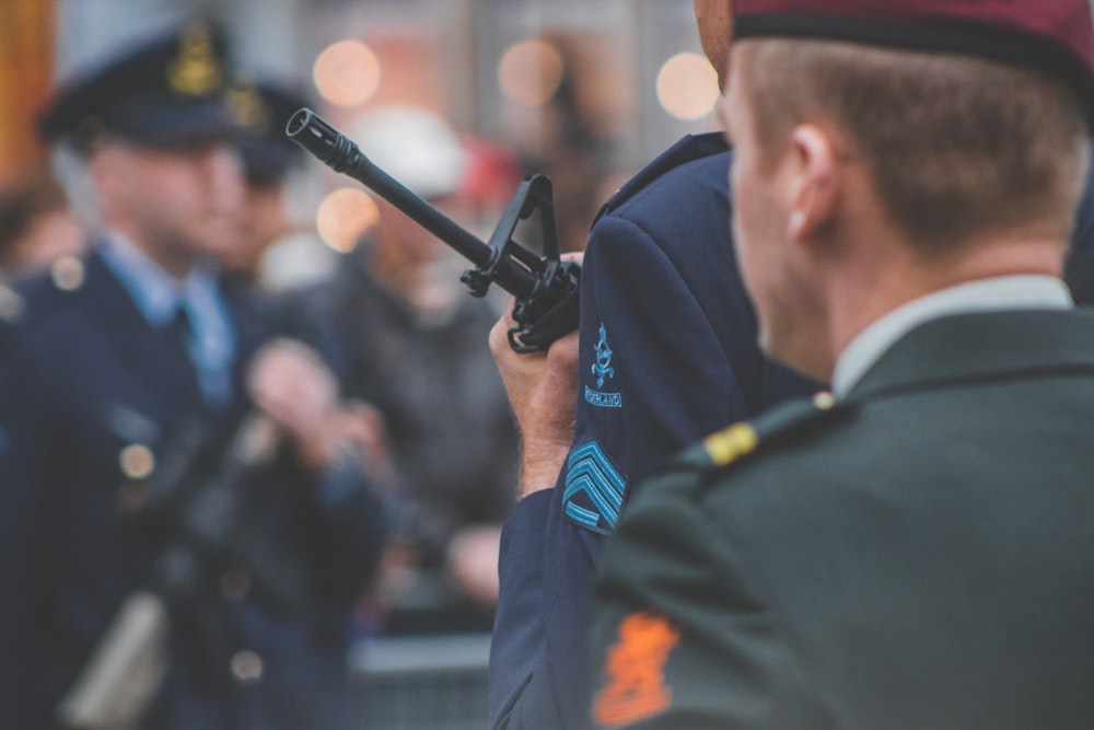 shallow depth of field photo of man holding rifle