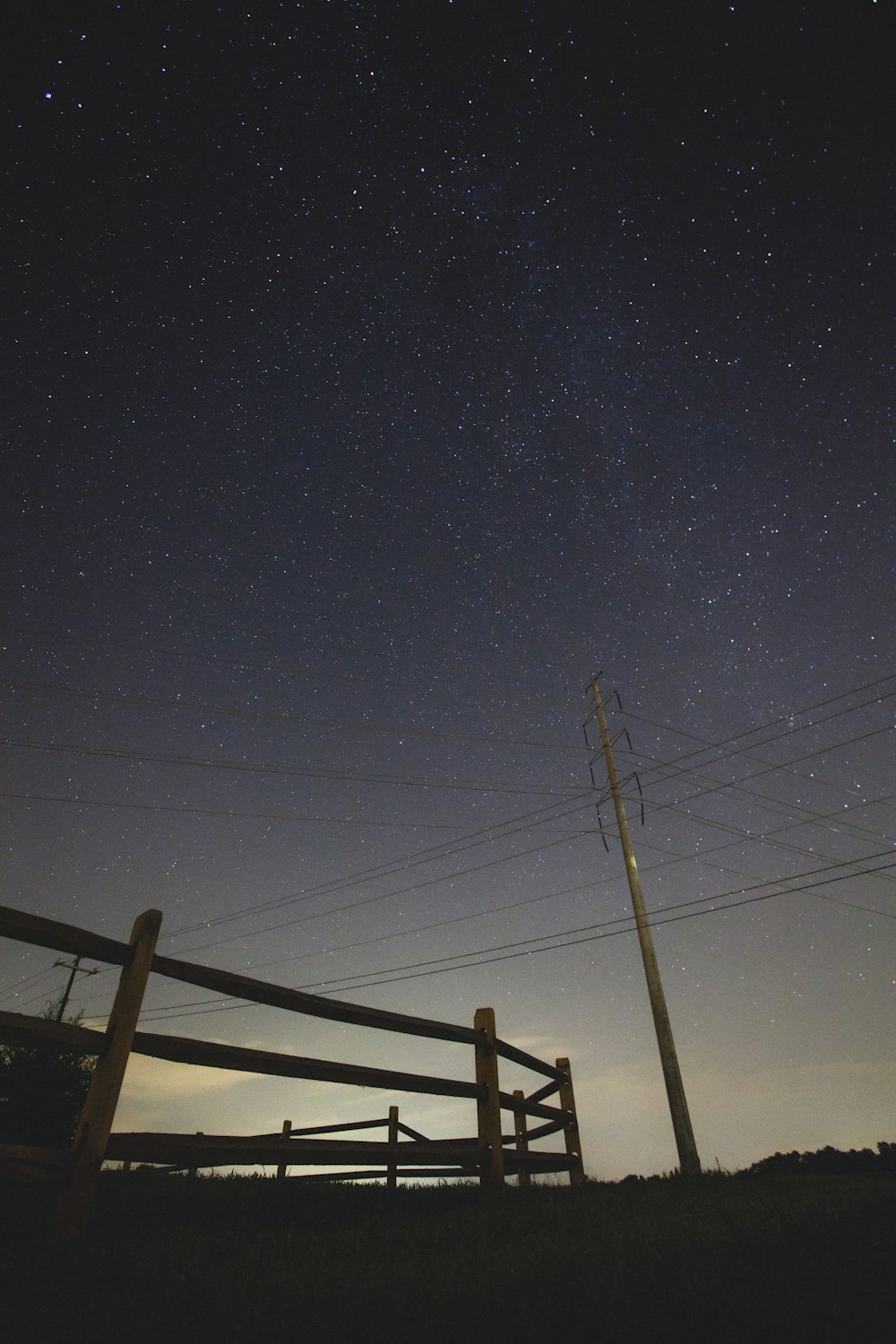 brown wooden fence and electrical post under stary skies