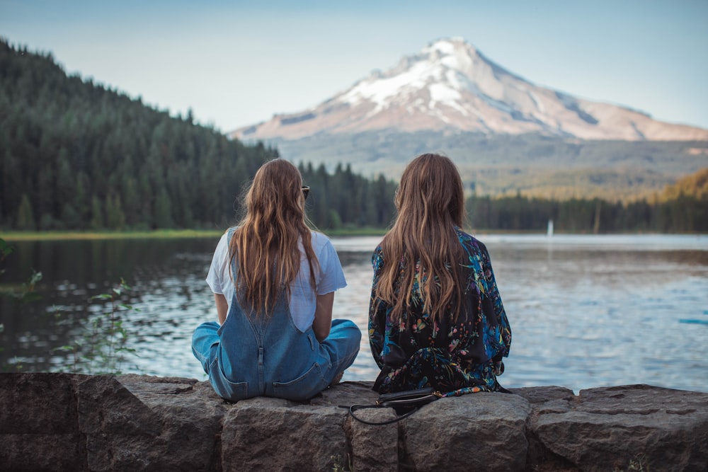 Frauen sitzen auf einem Felsen in der Nähe eines Gewässers