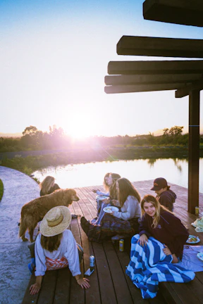 Guests enjoying a gourmet meal on the deck as the sun sets over the horizon.