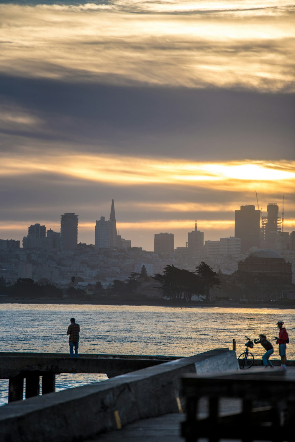 silhouette of people walking on boardwalk during golden hour