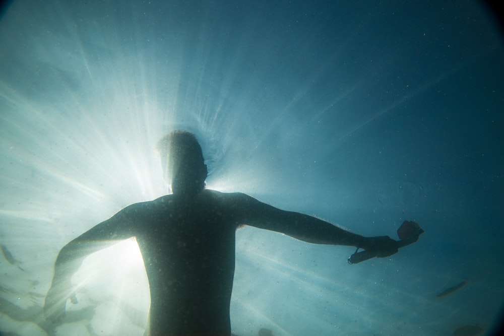 silhouette of man swimming at water during daytime