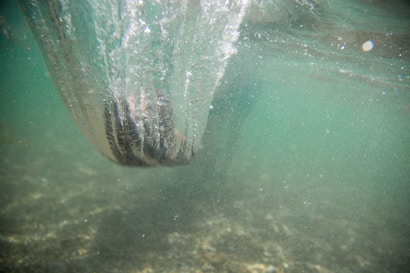 A view underwater capturing the turbulent movement of water as it swirls around a submerged object. The scene is filled with bubbles and a cloudy, greenish tint, suggesting motion and energy beneath the surface.