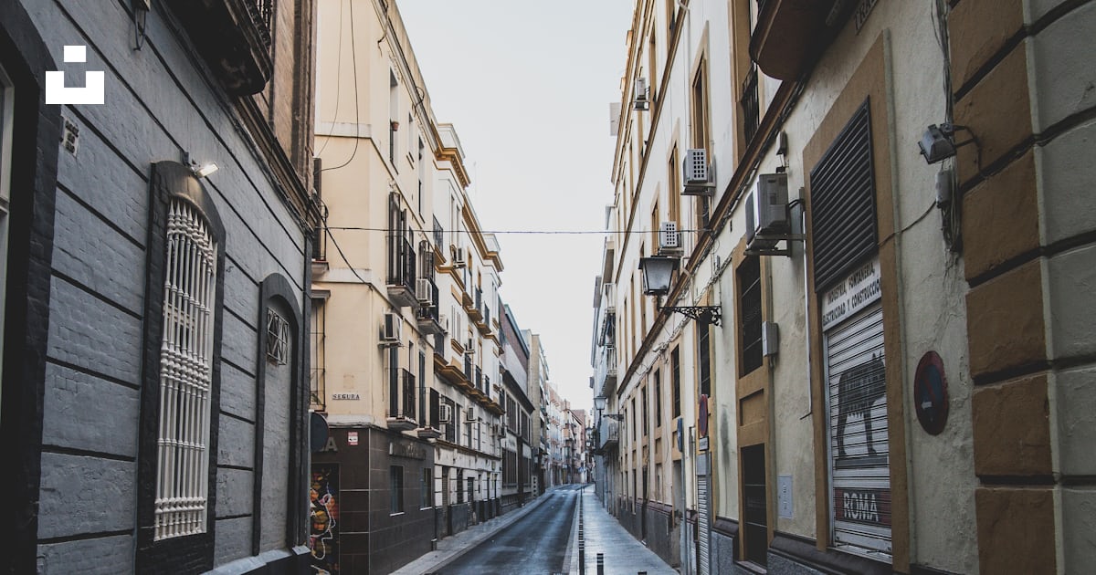 Empty road between brown concrete buildings during daytime photo – Free ...