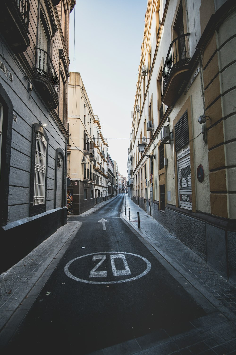 empty road between brown concrete buildings during daytime