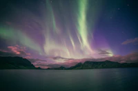 Aurora over a dark mountain lake, the sky above Kiruna in late winter