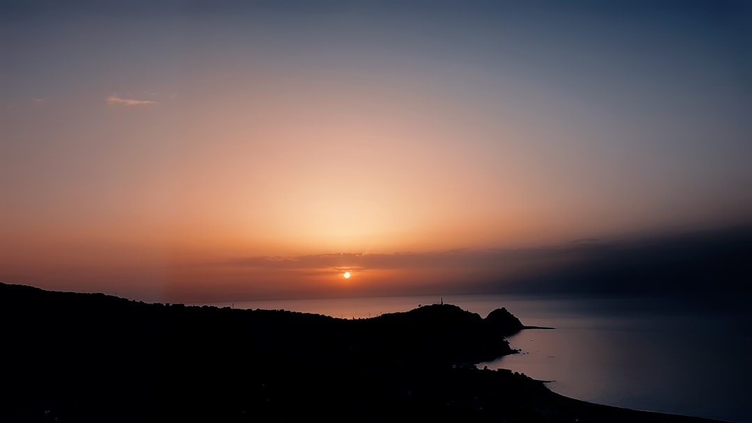 silhouette photography of mountain near body of water