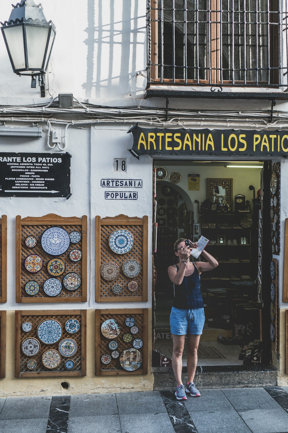 woman in pink shirt and blue denim shorts standing in front of the store