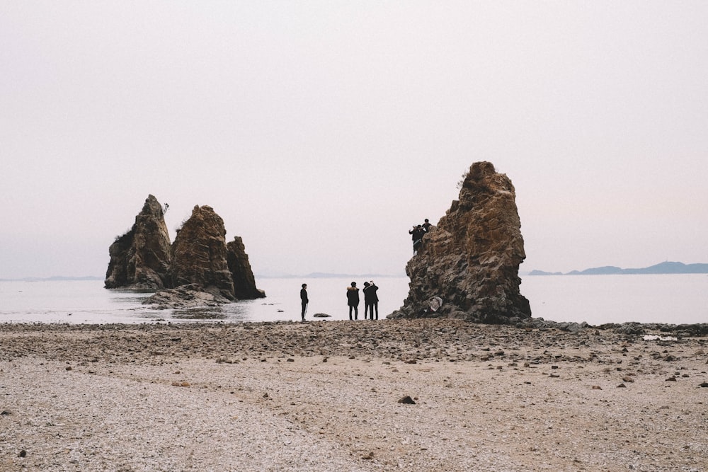 three people standing near brown rock formation