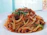 Close-up of a steaming plate of freshly made spaghetti with rich tomato sauce and basil.