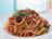 Close-up of a steaming bowl of pasta with fresh basil garnish