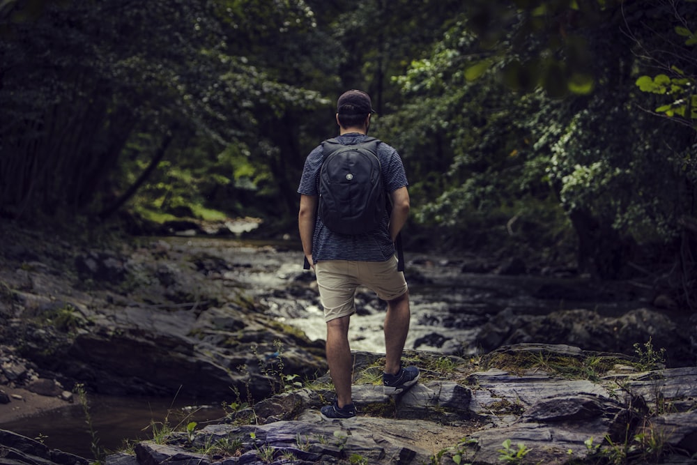 man standing on rock near body of water