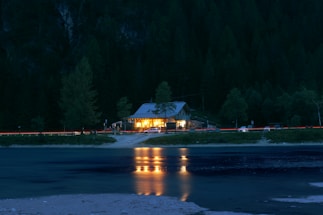 A cozy mountain cabin with a glowing lantern at dusk, inviting hikers to rest.