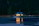 Cozy riverside cabin with warm glowing lights at dusk.