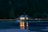 A cozy lakeside cabin with warm lights glowing inside during twilight.